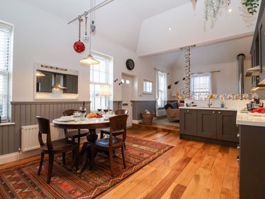 A kitchen and dining area with a round table, four chairs, a rug, and kitchen cabinets at Ebenezer Chapel in Knodishall nr Saxmundham