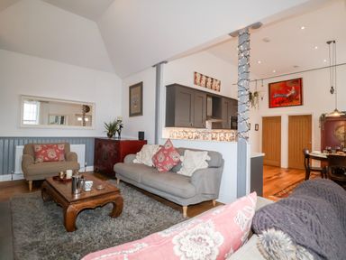 A living room with sofas a wooden coffee table and a kitchen area at Ebenezer Chapel in Knodishall nr Saxmundham