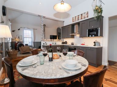 A kitchen dining area with a round marble table set with wine and bowls and a living room with armchairs at Ebenezer Chapel in Knodishall nr Saxmundham