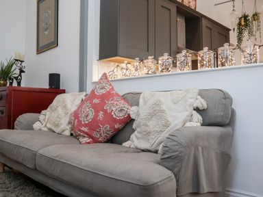 A grey sofa with cushions in a living room with jars containing string lights on a shelf at Ebenezer Chapel in Knodishall nr Saxmundham