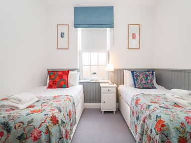 A bedroom with two single beds side by side with colorful pillows and floral bedspreads at Ebenezer Chapel in Knodishall nr Saxmundham