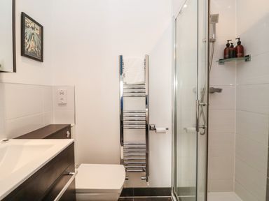 A bathroom with a toilet sink cabinet towel rack and glass shower at Ebenezer Chapel in Knodishall nr Saxmundham