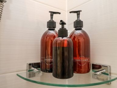 Three pump bottles on a glass shelf in a bathroom corner at Ebenezer Chapel in Knodishall nr Saxmundham