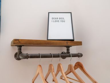 A wooden shelf with a framed sign and wooden hangers on a metal rod at Ebenezer Chapel in Knodishall nr Saxmundham