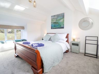 A bedroom with a wooden bed with folded towels and bedding at Ael Y Bryn in Ffestiniog