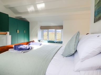 A bedroom with a bed and pillows green wardrobes and a window seat at Ael Y Bryn in Ffestiniog