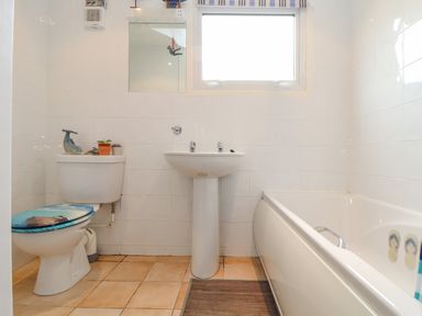 A bathroom with a toilet a sink a bathtub and a window at Villa 29 in Camelford