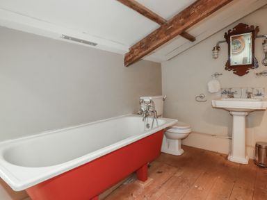 A bathroom featuring a bathtub, toilet, sink, and mirror at Penvar in Truro