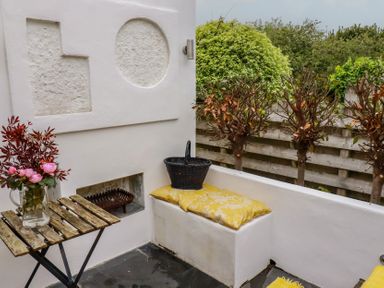 An outdoor seating area with a table and flowers at Penvar in Gerrans near Portscatho