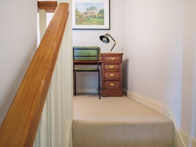 A small study area with a wooden desk green chair and a desk lamp at Lynton Cottage in Enstone