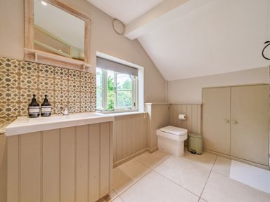 A bathroom with a sink under a mirror and a toilet next to a window at Lynton Cottage in Enstone