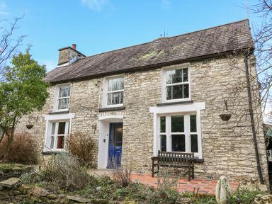 Stone house with blue door wooden bench and tiled porch at Cringoed House Llanarth near Aberaeron