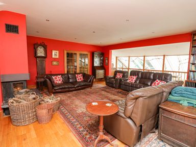 A living room with leather sofas and a fireplace with baskets of firewood at Cringoed House Llanarth near Aberaeron