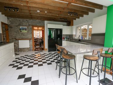 A kitchen with black and white checkered floor wooden ceiling beams and bar stools at Cringoed House Llanarth near Aberaeron