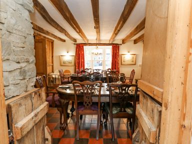 A dining room with wooden beamed ceiling and a large table set with plates and cutlery at Cringoed House Llanarth near Aberaeron