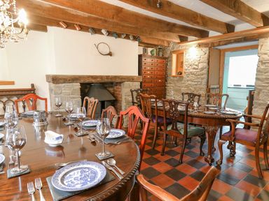 A dining room with wooden tables set with blue and white plates and wine glasses at Cringoed House Llanarth near Aberaeron