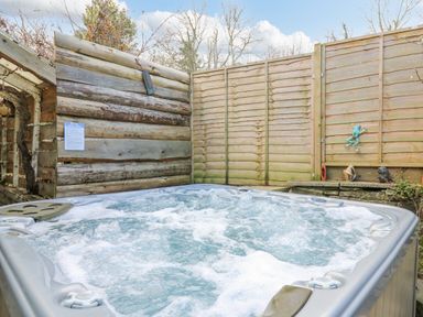 An outdoor hot tub with bubbling water surrounded by wooden fencing and wall decorations at Cringoed House Llanarth near Aberaeron