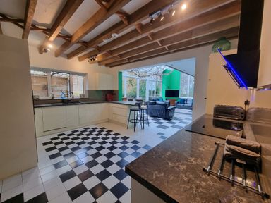 A kitchen with black and white checkered floor opening to a living area with sofas and large windows at Cringoed House in Llanarth near Aberaeron