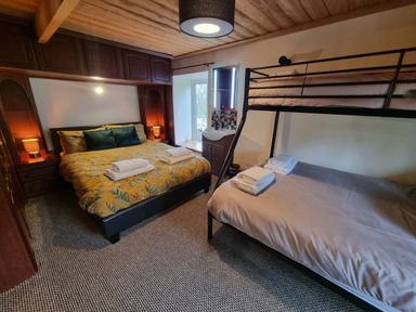 A bedroom with a double bed with floral bedding and bunk beds with towels placed on each bed at Cringoed House in Llanarth near Aberaeron