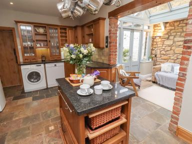A kitchen with a washing machine and flowers on the countertop at Rose House in Alnmouth
