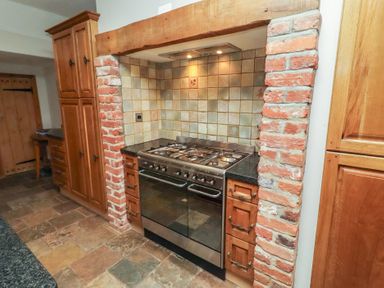 A kitchen with a stove and cabinets at Rose House in Alnmouth
