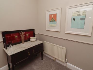 A hallway with a table and framed artwork at Rose House in Alnmouth