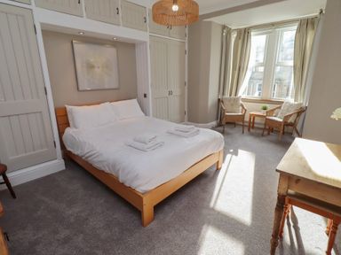 A bedroom with a bed and chairs at Rose House Alnmouth