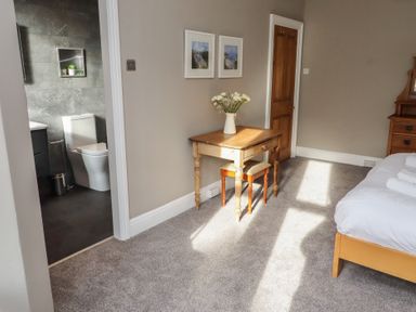 A bedroom with a bed, table, and chairs at Rose House in Alnmouth