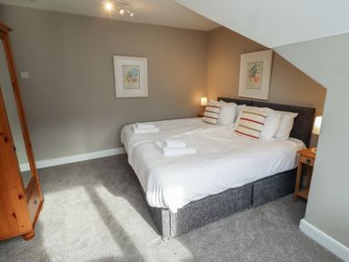 A bedroom with two beds and a nightstand at Rose House in Alnmouth