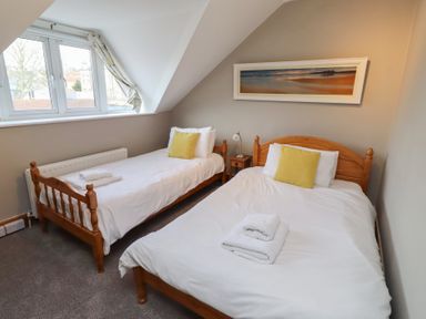 A bedroom with two single beds and a window at Rose House in Alnmouth