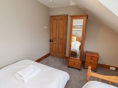 A bedroom with a bed, mirror, and drawer at Rose House in Alnmouth