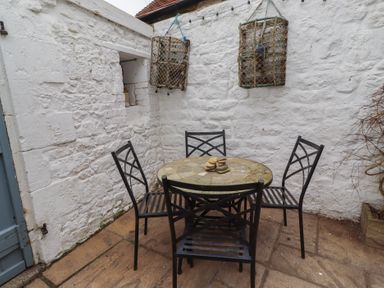 An outdoor patio with a table and chairs at Rose House in Alnmouth