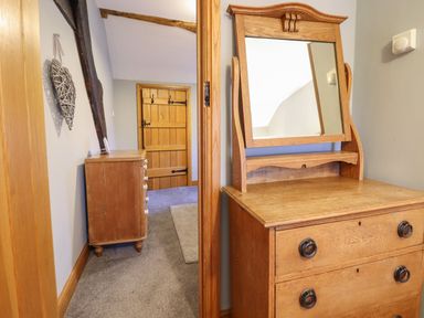 A hallway with wooden furniture a dresser with a mirror and a chest of drawers near a wooden door at Ynys in Dyffryn Ardudwy
