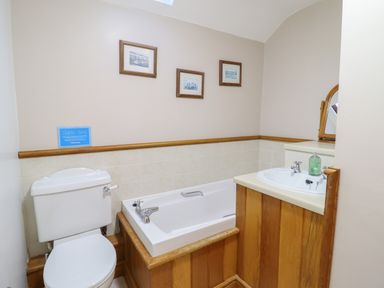 A bathroom with a toilet bathtub sink and three framed pictures on the wall at Ynys in Dyffryn Ardudwy