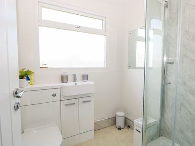 A bathroom with a toilet sink cabinet shower with glass door and frosted window at Dollys Lookout in Kessingland