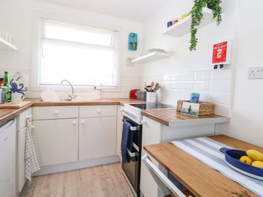 A kitchen with a sink oven countertop and small table with fruit bowl at Dollys Lookout in Kessingland