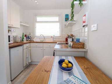 A kitchen with wooden countertops a blue bowl of lemons and a magazine on a wooden table at Dollys Lookout in Kessingland