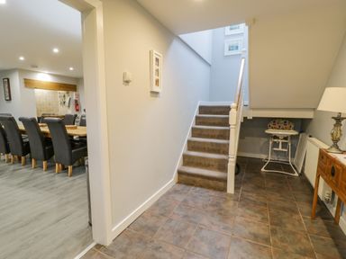 A hallway with stairs and a dining area with chairs at Bodrual Cottage in Rhosbodrual near Caernarfon