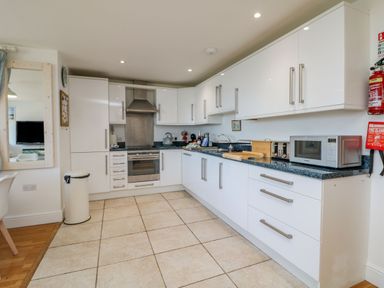 A kitchen with white cabinets a stainless steel oven and microwave on the counter at Beachcomber in Porthcurno near Sennen