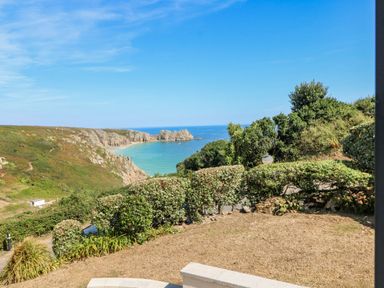 A coastal landscape with cliffs shrubs and a view of the ocean at Beachcomber in Porthcurno near Sennen