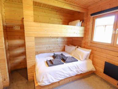 A wooden room with a bunk bed and folded towels on the lower bed at iLodge Ultra Kenwick near Louth