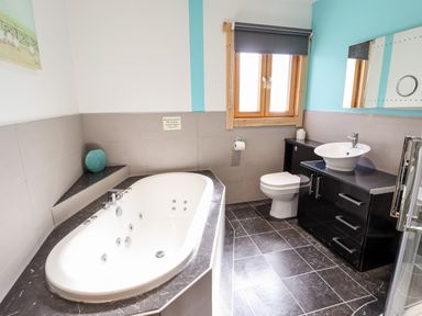A bathroom with a bathtub toilet sink and window at iLodge Ultra Kenwick near Louth