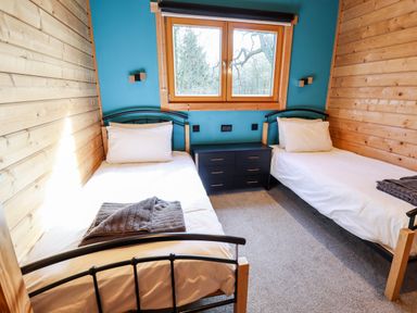 A bedroom with two single beds and a chest of drawers under a window at iLodge Ultra in Kenwick near Louth