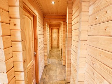 A wooden hallway with multiple doorways and a tiled floor at iLodge Ultra Kenwick near Louth