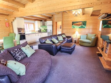 A living room with sofas a chandelier a kitchen and dining chairs at iLodge 73 Kenwick near Louth