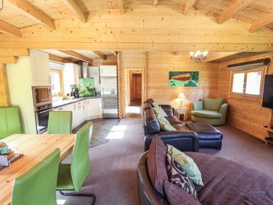 A living room and kitchen with green dining chairs and a brown sofa at iLodge 73 in Kenwick near Louth
