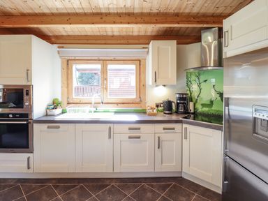 A kitchen with white cabinets a window above the sink a coffee maker and a stainless steel refrigerator at iLodge 73 Kenwick near Louth