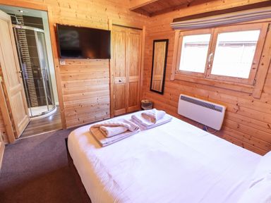 A bedroom with a bed with towels a wall-mounted television a window and an en suite bathroom at iLodge 73 in Kenwick near Louth