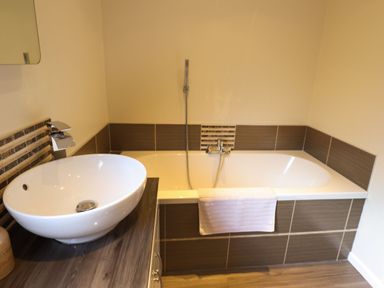 A bathroom with a bathtub with a towel and a sink on a wooden countertop at iLodge 73 Kenwick near Louth