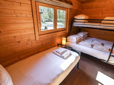 A wooden bedroom with a single bed with towel and a bunk bed with pillows and towel at iLodge 73 Kenwick near Louth